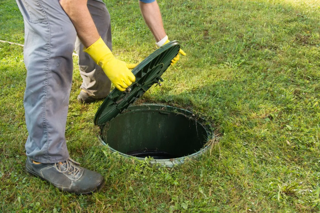 A man opening the cover of a septic tank