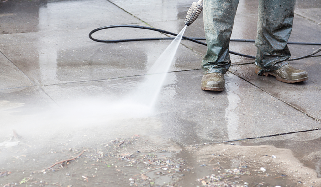 A person power washing a concrete floor