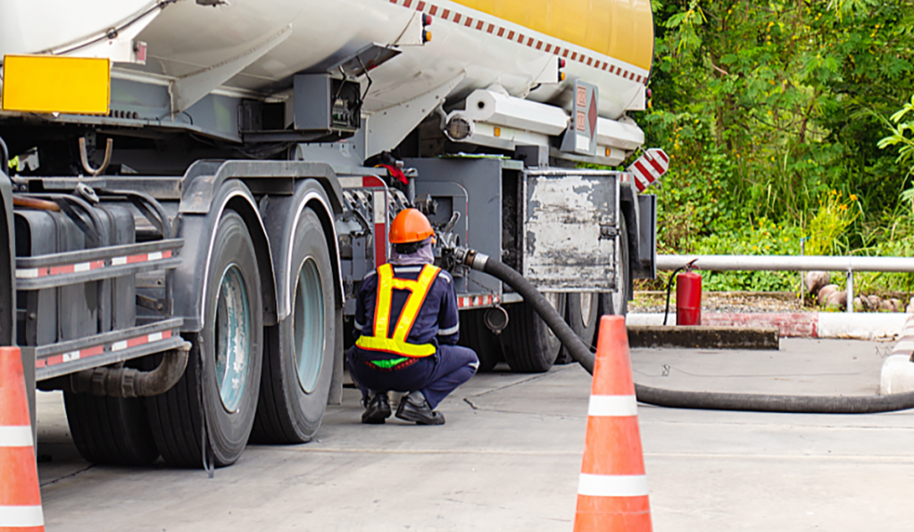 Liquid waste tanker truck being serviced by a trained worker