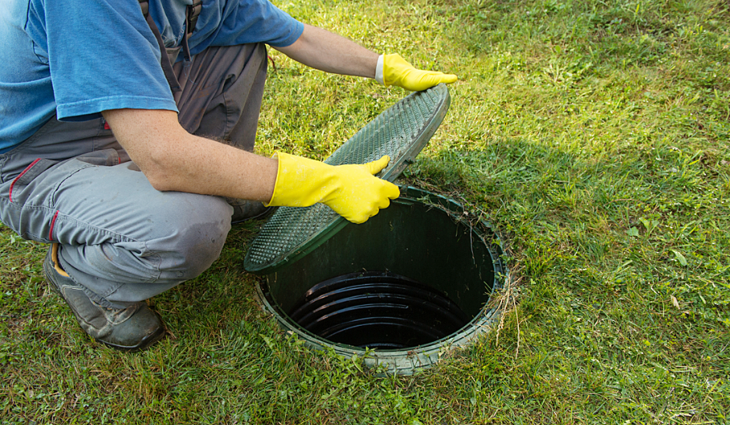 Technician inspecting a septic tank access point