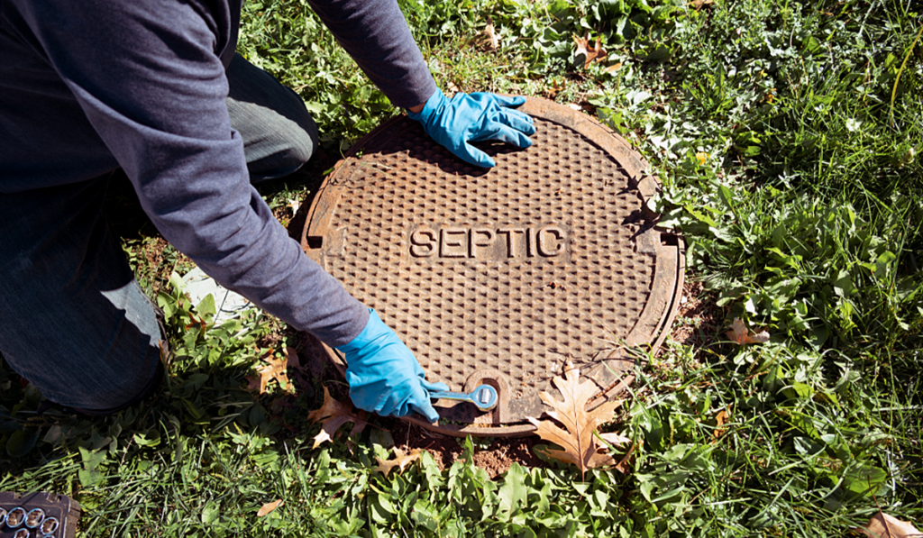 Worker inspecting a septic tank access cover